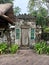 old ornate doorway with frangipani trees and thatched roof houses