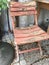 Old outdoor wooden chair with red paint peeling off