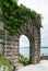 Old overgrown stone castle gate with a lake behind