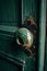 A old oxidized bronze door handle on a green wooden door. Generative AI image.