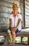 Old Padaung woman in traditional dress and with metal rings around her neck, arms and legs is sitting on a staircase in house.