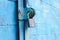 old padlock on a blue metal door with wooden planks cracked paint and rust