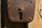 An old padlock rusty weighs on a wooden door.