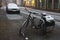 Old parking bicycle and car under snow at empty street. Abandoned bike.