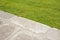 Old paving made with stone blocks in a pedestrian zone and fresh green lawn