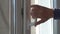 Old person hand closes plastic window holding white handle