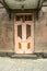 Old pink double doors with Windows covered with wrought iron bars and Golden figures on the facade of a stone house with a canopy