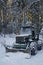 Old plough tractor covered with snow in the forest
