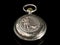 Old pocket watch on a black reflective surface, closed lid with hunting motive