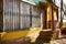 Old porch of an abandoned house. frayed yellow paint on the facade, door, rectangular column and windows with bars