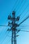 Old power utility and street light pole with cables and wires against blue sky