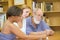 Old professor with multiracial group studying in library