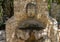 Old public stone fountain with face in Eze, France