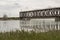 Old railway bridge over the river. Motor boat under the bridge. The reeds on the shore