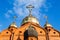 Old red brick Christian church with gold and gilded domes against a blue sky. Concept faith in god, orthodoxy, prayer