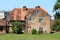 Old red brick suburban family house with cracked facade and windows with dilapidated wooden frames surrounded with grass and trees