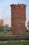 Old red brick water tower near the rails against the sky.