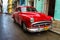 Old red car in a shabby street in Havana