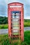 Old red English phone booth in countryside