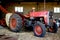 Old red farm tractor inside a barn