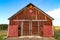 Old red painted weathered barn all alone in a field