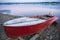 Old red rowboat lying at shore