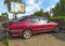 Old red rusty dented Toyota Carina parked