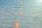 Old red styrofoam buoys on the rope lying on the beach of the sea