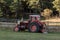 Old red tractor next to ranch in autumn on a sunny day