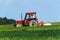 Old red tractor sails the meadow. Summer work on an agricultural farm.