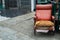 Old red upholstered chair that is not being used that was abandoned beside a pile of rubbish