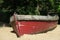 Old red wooden clinker rowboat on a beach