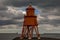 The old, red, wooden Herd Groyne Lighthouse in South Shields, stands out against the cloudy sky