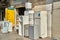 Old refrigerators and washing machines with heavy signs of use and partially missing doors and covers are for sale on the side of