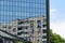 Old residential multi-storey panel house reflected in the mirrored wall of an office building. Comparison of modern mirror facade