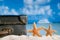 Old retro antique suitcase on beach with starfish, sea and sky b