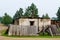 An old, rickety wooden barn stands with an open door behind a fallen fence in the Northern village