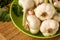 Old ripe garlic in a green plastic bowl on a rustic wooden cutting board