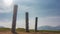 Old ritual wooden totem poles stand on the hillside.