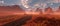 Old road through red rocky desert landscape with cloudy sky and