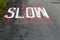 Old road SLOW road markings sign with worn and faded red background