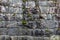 Old rock wall with neatly fitted blocks of rock and some green