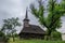 Old Romanian traditional wooden church surrounded by trees in countryside in Transylvania region, Romania