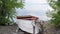 Old rowing fishing boat are tied and marooned with chain to the river shore.