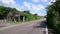 Old ruin covered and overgrown with green plants, empty road, blue sky