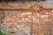 Old ruined brick wall with some concrete and cracks. Damaged antique brick wall