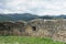 Old ruined stone wall of ancient Cisnadioara fortress in Sibiu,  Romania. Green grass all around. Mountains in background