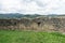 Old ruined stone wall of ancient Cisnadioara fortress in Sibiu,  Romania. Green grass all around. Mountains in background