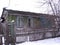 An old ruined wooden house with an uninhabited unnecessary building behind a fence with closed Windows a dilapidated abandoned