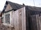 An old ruined wooden house with an uninhabited unnecessary building behind a fence with closed Windows a dilapidated abandoned